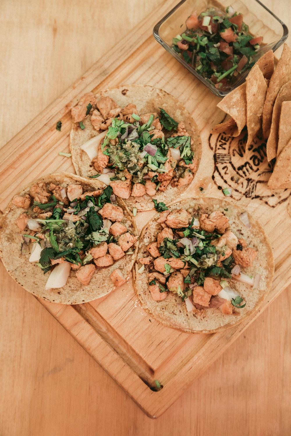 Tacos on a wooden cutting board with cilantro