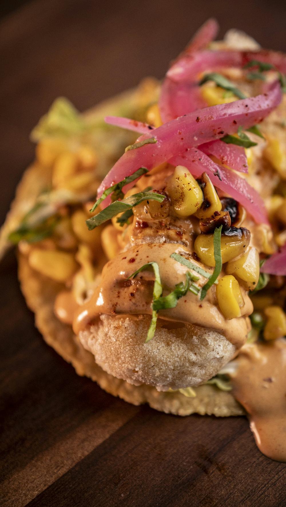 Taco topped with roasted corn and pickled onions